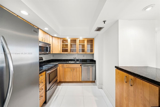 1775 Washington Ave Unit 11C, Miami Beach, FL 33139 - kitchen featuring appliances with stainless steel finishes, a sink, recessed lighting, dark stone counters, and glass insert cabinets
