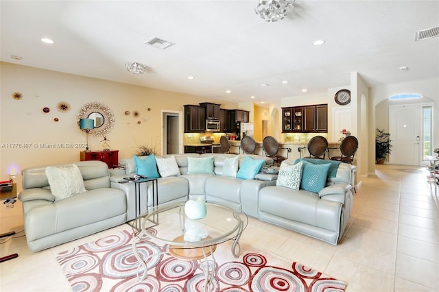 living area featuring arched walkways, visible vents, recessed lighting, and light tile patterned floors
