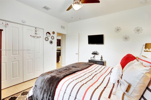 bedroom with a closet, visible vents, a ceiling fan, and light tile patterned floors