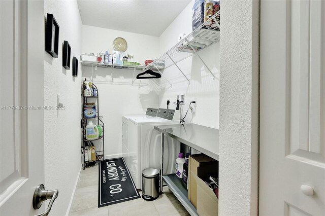 laundry room with light tile patterned flooring, washer and clothes dryer, and laundry area