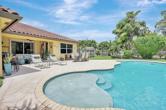 outdoor pool with fence, a patio area, and a ceiling fan