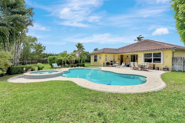 view of pool featuring fence, a yard, a pool with connected hot tub, and a patio