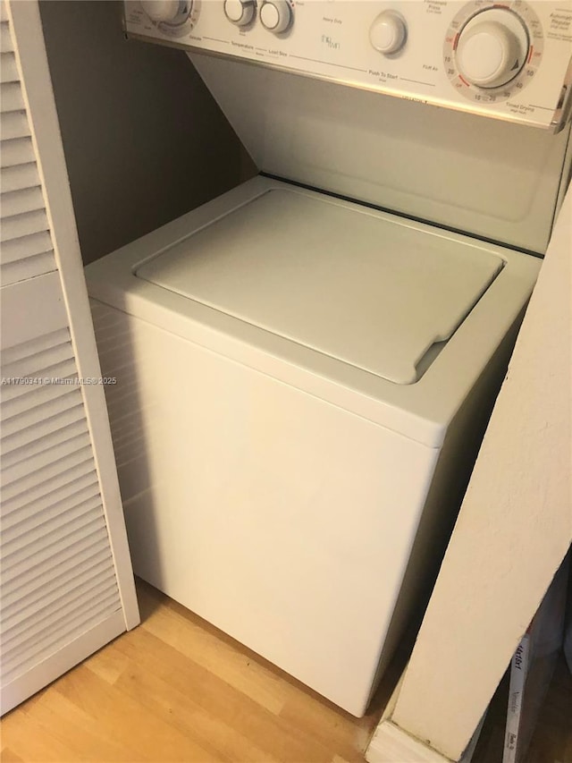 clothes washing area with washer / clothes dryer, light wood finished floors, and laundry area