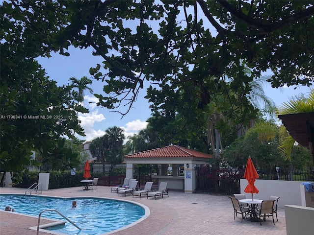 community pool with fence and a patio