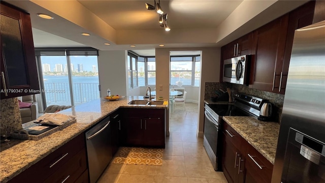 16570 NE 26th Ave Unit 4A, North Miami Beach, FL 33160 - kitchen featuring stainless steel appliances, a sink, light tile patterned floors, a tray ceiling, and light stone counters