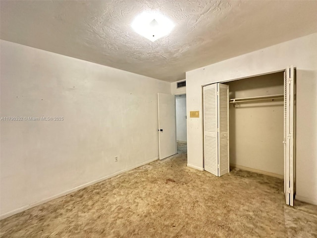 unfurnished bedroom with visible vents, carpet floors, a textured ceiling, and a closet
