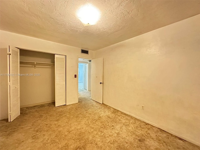 unfurnished bedroom with a closet, carpet flooring, a textured ceiling, and visible vents