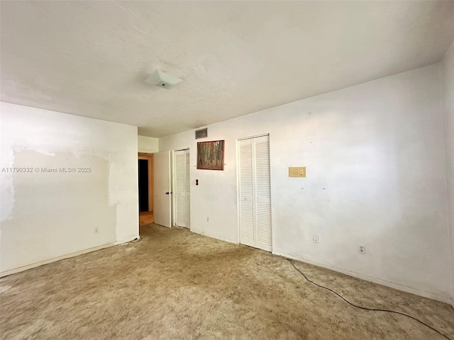 carpeted empty room featuring visible vents
