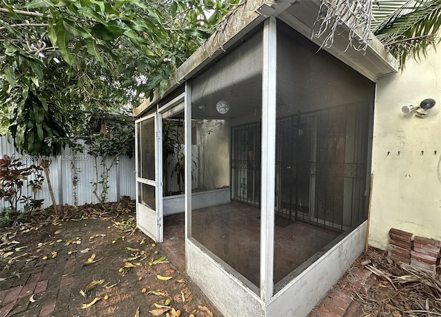 view of property exterior with fence and a sunroom