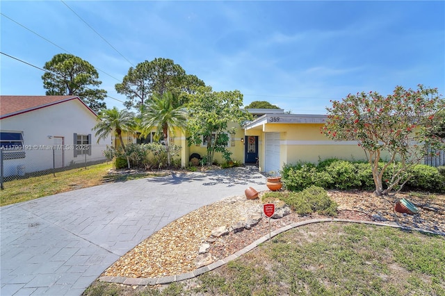 view of front of property with stucco siding, decorative driveway, an attached garage, and fence