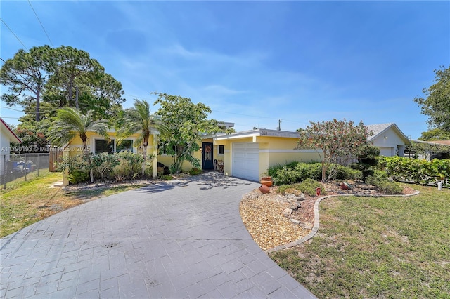 view of front of home featuring a front yard, a garage, decorative driveway, fence, and stucco siding