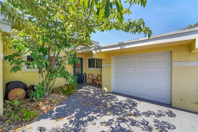 view of front of home with concrete driveway, an attached garage, and stucco siding