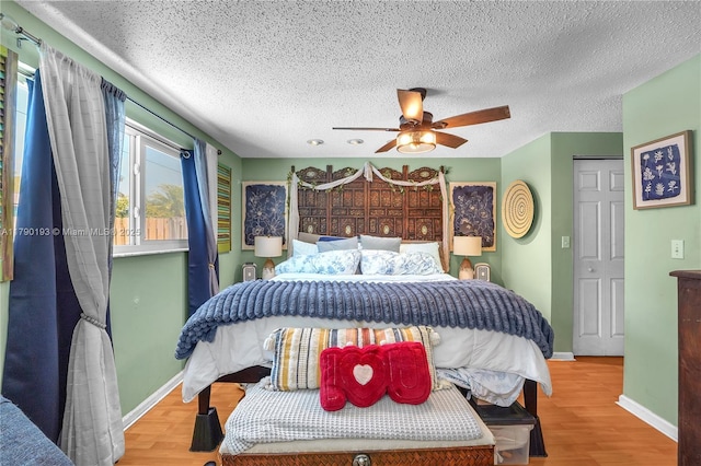 bedroom featuring baseboards, a textured ceiling, ceiling fan, and wood finished floors