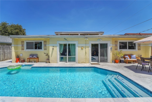 rear view of house with a patio, a fenced in pool, fence, and stucco siding