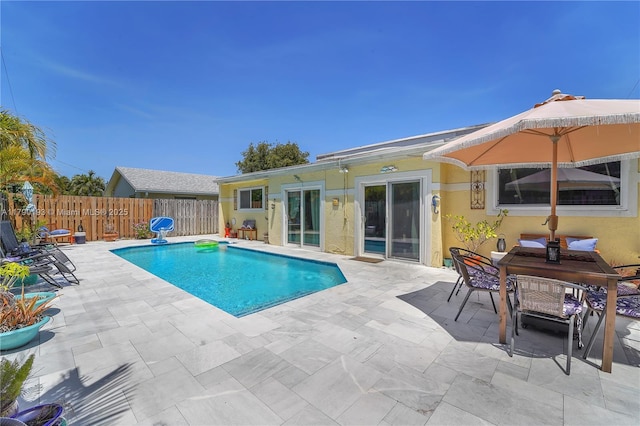 view of pool with fence, a fenced in pool, outdoor dining space, and a patio area