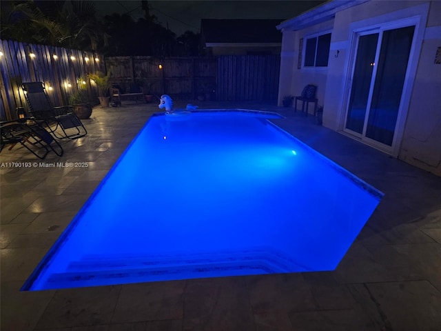 pool at twilight with a patio, a fenced in pool, and a fenced backyard