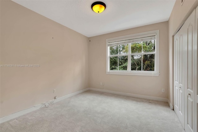 empty room featuring light carpet and baseboards
