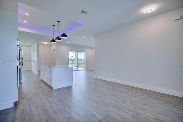 5224 Columbus Blvd, Sebring, FL 33872 - kitchen with hanging light fixtures, open floor plan, light wood-type flooring, white cabinetry, and freestanding refrigerator