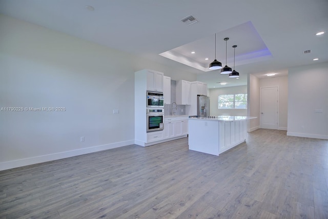 5224 Columbus Blvd, Sebring, FL 33872 - kitchen featuring appliances with stainless steel finishes, open floor plan, a tray ceiling, recessed lighting, and white cabinets