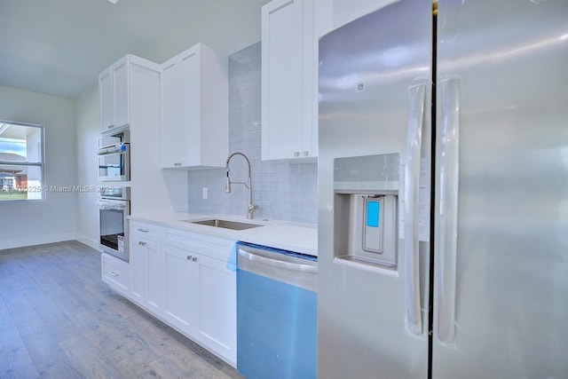 5224 Columbus Blvd, Sebring, FL 33872 - kitchen featuring stainless steel appliances, a sink, tasteful backsplash, white cabinets, and light wood-type flooring