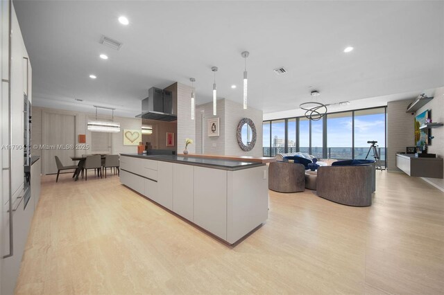 1000 Brickell Plz Unit Ph5603, Miami, FL 33131 - kitchen with wall chimney exhaust hood, light wood-style floors, dark countertops, modern cabinets, and expansive windows