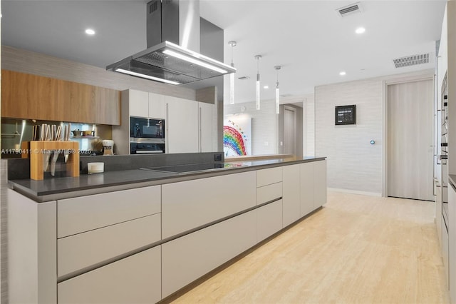 1000 Brickell Plz Unit Ph5603, Miami, FL 33131 - kitchen with island range hood, black appliances, dark countertops, white cabinetry, and light wood finished floors