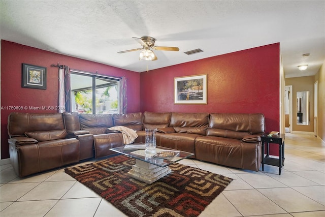 living area featuring a textured wall, visible vents, light tile patterned floors, a textured ceiling, and ceiling fan