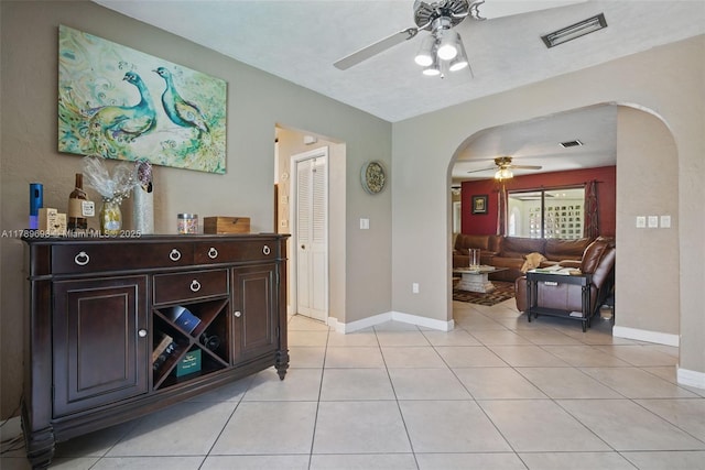 interior space with light tile patterned floors, arched walkways, visible vents, and baseboards