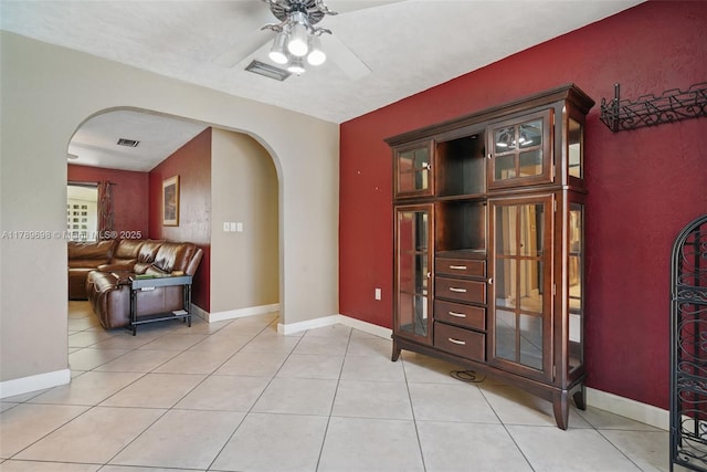 interior space featuring light tile patterned floors, visible vents, arched walkways, and ceiling fan