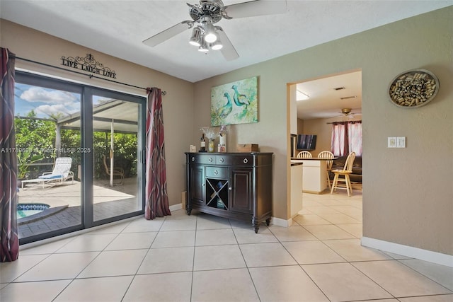 doorway to outside featuring a ceiling fan, baseboards, and light tile patterned floors