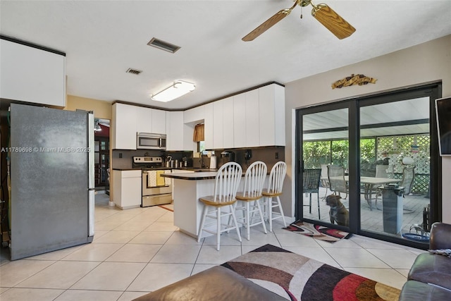 kitchen featuring a peninsula, dark countertops, visible vents, ceiling fan, and appliances with stainless steel finishes