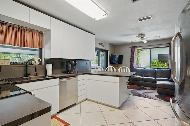 kitchen featuring open floor plan, a peninsula, dark countertops, and appliances with stainless steel finishes