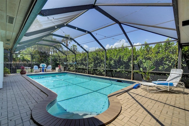 outdoor pool featuring glass enclosure and a patio