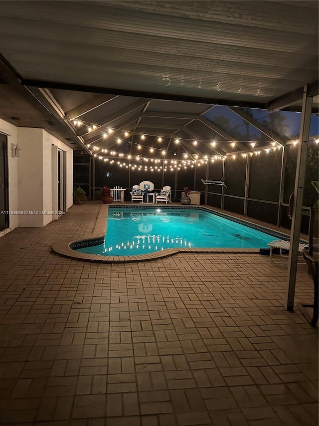 outdoor pool with glass enclosure and a patio