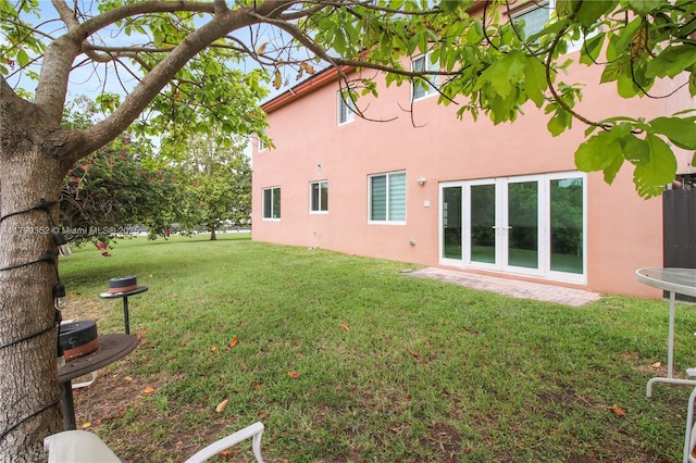 rear view of house with a lawn and stucco siding