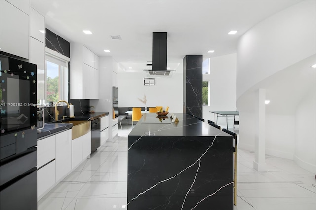 kitchen featuring a sink, island range hood, black appliances, modern cabinets, and white cabinets