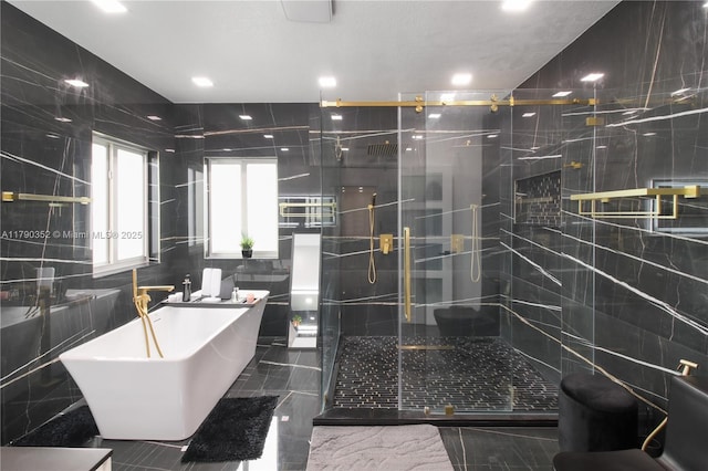 bathroom with tile walls, a freestanding tub, marble finish floor, and a stall shower