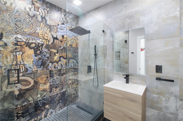 bathroom with tile walls, walk in shower, and vanity