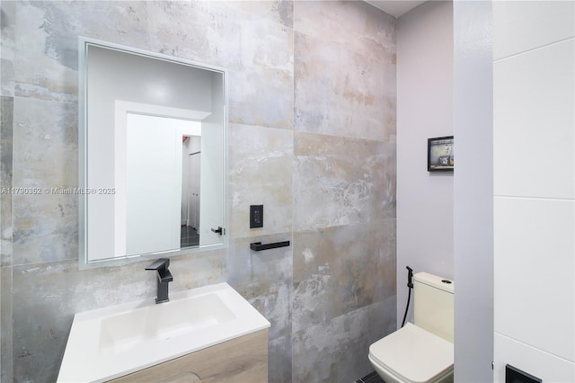 half bath featuring toilet, vanity, and tile walls