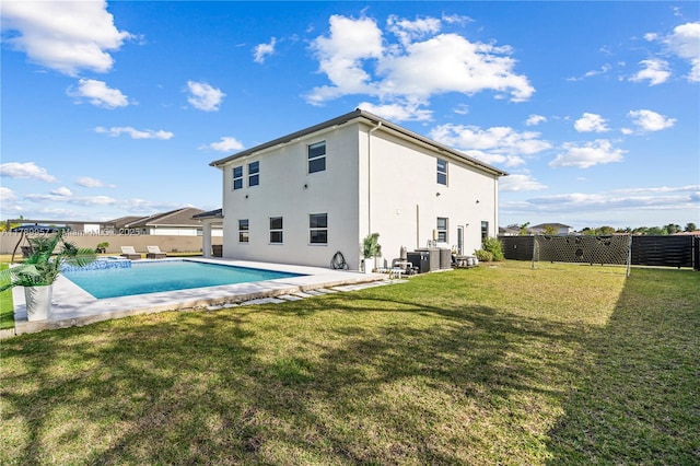 back of house with stucco siding, a fenced in pool, a fenced backyard, and a lawn