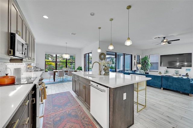 8650 NW 39th Ct, Coral Springs, FL 33065 - kitchen with a breakfast bar, a sink, white appliances, light countertops, and light wood-style flooring