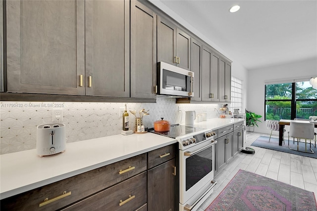 8650 NW 39th Ct, Coral Springs, FL 33065 - kitchen with light countertops, white range with electric cooktop, recessed lighting, stainless steel microwave, and backsplash