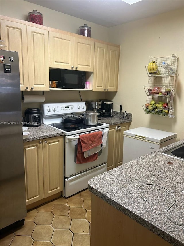 2480 W 67th Pl Unit 12-12, Hialeah, FL 33016 - kitchen with light brown cabinetry, freestanding refrigerator, black microwave, white range with electric cooktop, and light tile patterned floors