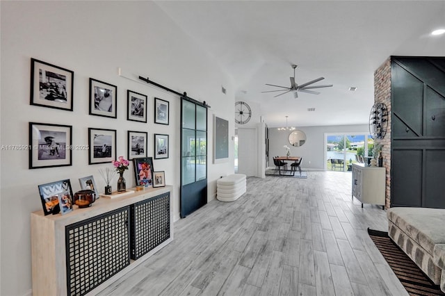 interior space featuring a barn door, light wood-type flooring, lofted ceiling, and baseboards