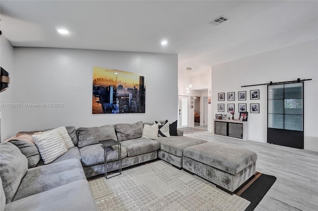 living area featuring a barn door, wood finished floors, visible vents, and recessed lighting
