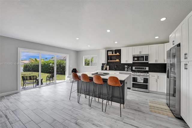 kitchen with a kitchen breakfast bar, light countertops, white cabinets, baseboards, and appliances with stainless steel finishes