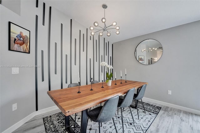 dining area with a chandelier, light wood-style floors, and baseboards
