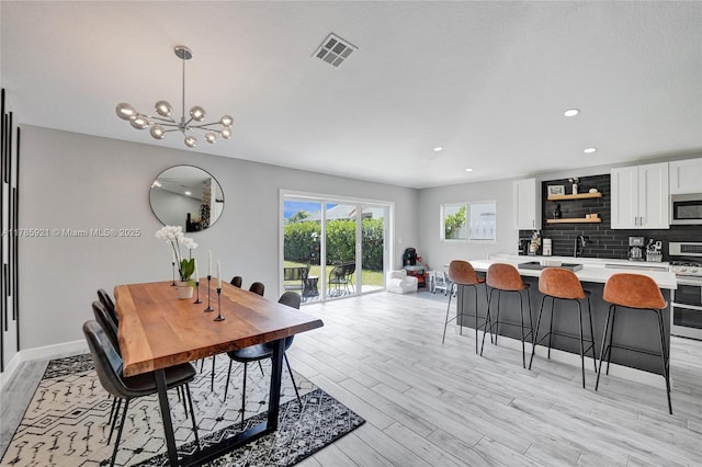 dining space with light wood-type flooring, baseboards, a notable chandelier, visible vents, and recessed lighting