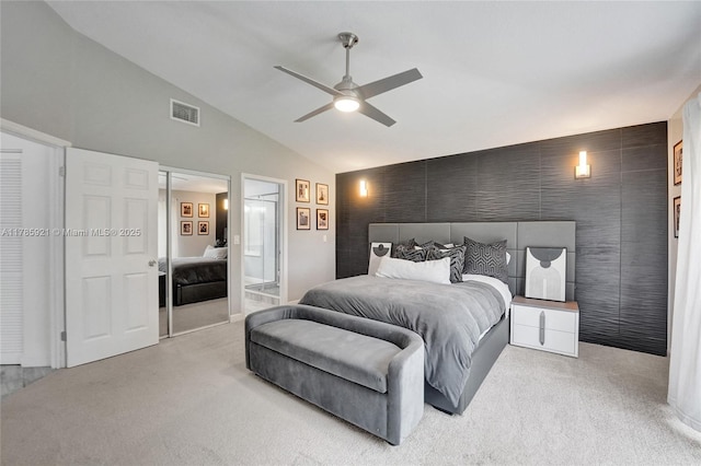 bedroom with lofted ceiling, visible vents, a ceiling fan, light carpet, and ensuite bath