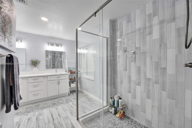bathroom featuring wood finished floors, a textured ceiling, a stall shower, vanity, and recessed lighting